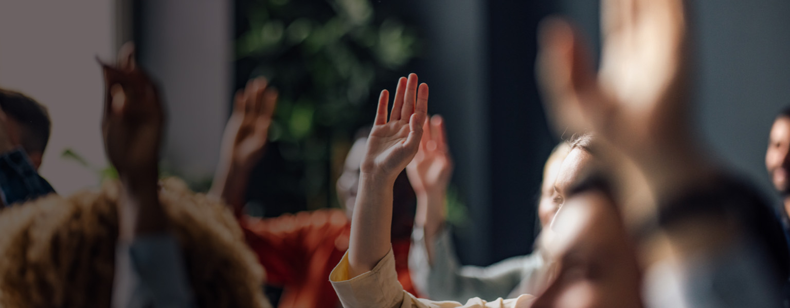 Image of people with hands in the air asking questions